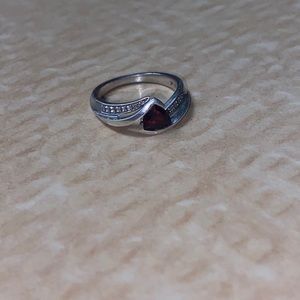 Silver ring with a burgundy birth stone.